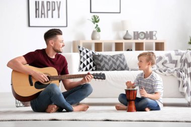 Küçük bir çocuk ve babası evde oynarken müzik aletleri ile