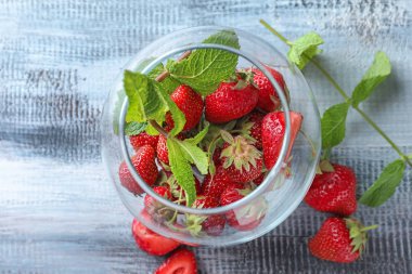 Ahşap arka plan üzerinde olgun çilek ile cam kase