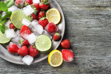 Buz küpleri, çilek ve ahşap masa üzerine dilimlenmiş narenciye ile plaka