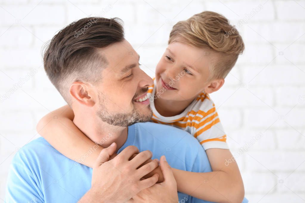 Little boy and his dad on light background