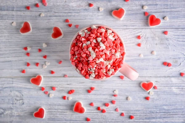 Ahşap masa üzerinde lezzetli kalp şeklinde şeker ile Kupası