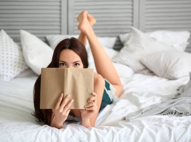 Güzel ve genç birbayan okuma kitabı evde yatak odasında sabah