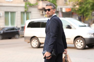 Caddenin üzerinde alışveriş torbaları ile takım elbiseli Olgun yakışıklı