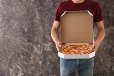 Grunge zemin üzerine lezzetli pizza kutusu tutan genç adam. Gıda dağıtım hizmeti