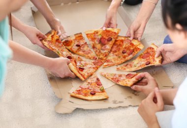 Genç insanlar sıcak lezzetli pizza dilimlerini karton kutu