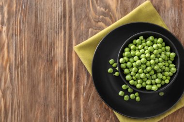 Ahşap masa üzerinde lezzetli taze yeşil bezelye ile kase