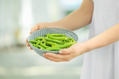 Hasır sepet taze yeşil bezelye açık havada, closeup ile tutan genç kadın