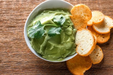 Lezzetli guacamole ve ahşap arka plan üzerinde gevrek ekmek kase