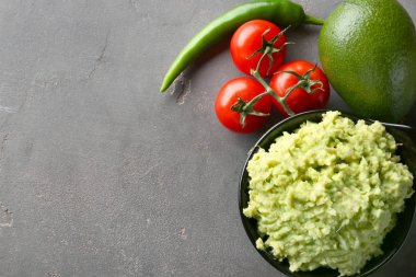 Gri dokulu arka plan üzerinde malzemelerle lezzetli guacamole