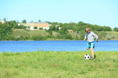 Sevimli çocuk futbol oynayan nehir kenarında