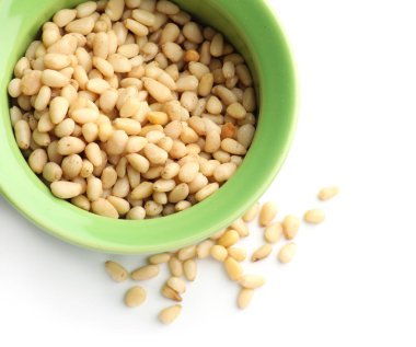 Beyaz arka plan üzerinde çam fıstığı ile kase