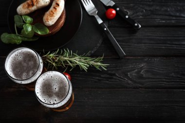 Izgara sosis ve ahşap masa üzerinde otlar ile lezzetli bira gözlük