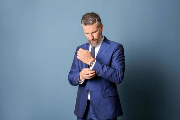 Handsome mature man in elegant suit on color background