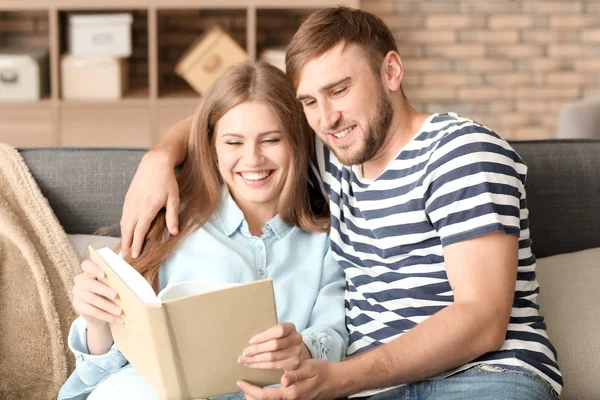 Happy young couple with book resting at home