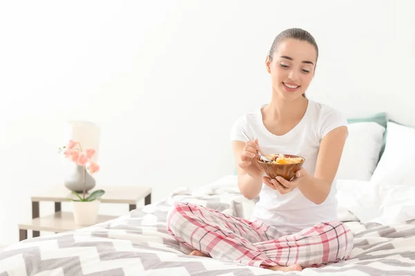 美しい若い女性の寝室で朝食のおいしいオートミールを食べる — ストック写真