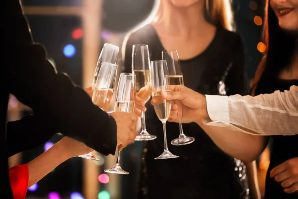 Young people clinking glasses with champagne at birthday party in club