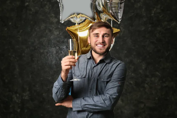 誕生日用風船と暗い背景にシャンパン グラスを持つ若者 — ストック写真