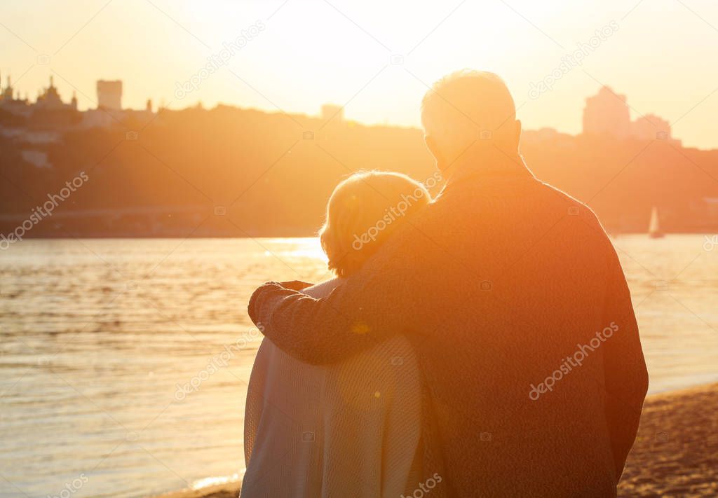 Happy mature couple on riverside at sunset