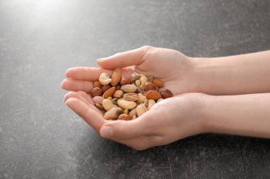 Farklı fındık gri arka plan üzerinde tutan kadın