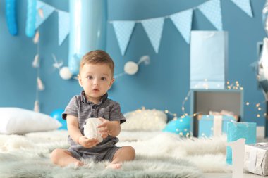 Doğum günü partisi için dekore edilmiş oda kabarık halıya oturup şirin küçük çocuk