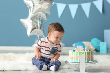 Tüylü halı odada oturan Doğum günü pastası ile şirin küçük çocuk