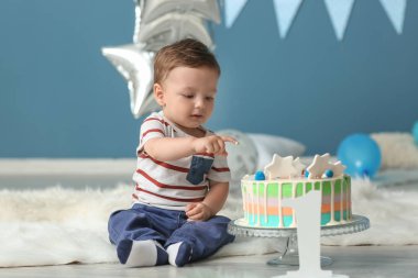 Tüylü halı odada oturan Doğum günü pastası ile şirin küçük çocuk