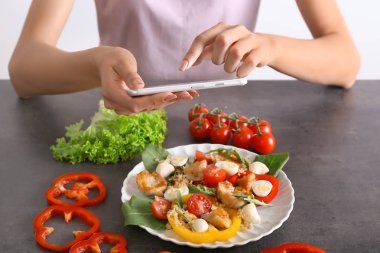 Genç kadın alarak fotoğraf lezzetli tavuk salatası masasında cep telefonunuzla