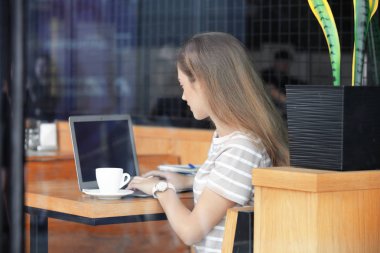 Genç kadın freelancer kafede çalışan dizüstü bilgisayar ile camdan görüntülemek