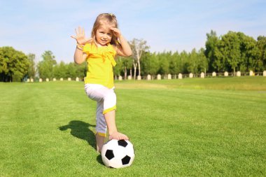 Güneşli günde parkta futbol oynayan sevimli küçük kız