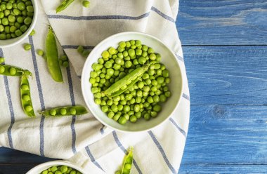 Ahşap masa üzerinde yeşil bezelye ile kase