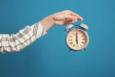 Çalar saat renk arka plan üzerinde tutan kadın. Zaman yönetimi kavramı