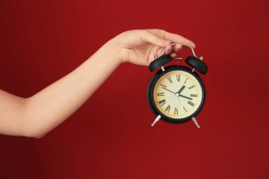 Çalar saat renk arka plan üzerinde tutan kadın. Zaman yönetimi kavramı