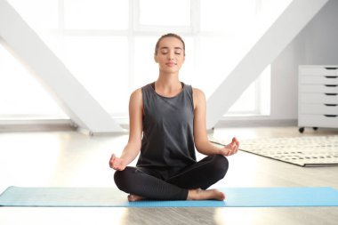 Evde yoga yapan genç bir kadın.