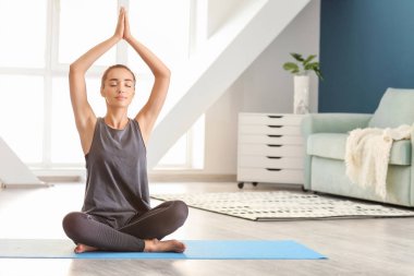 Evde yoga yapan genç bir kadın.