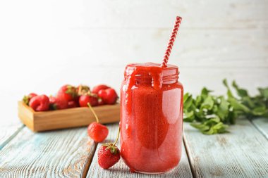 Cam kavanoz ile ışık ahşap masa üzerinde çilek güler yüzlü