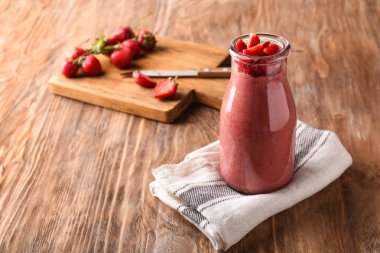 Ahşap masa üzerinde çilek güler yüzlü şişesiyle