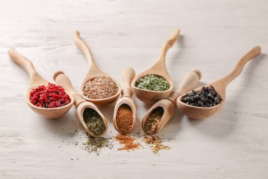 Kaşık ve kepçe ile ahşap arka plan üzerinde farklı kuru baharat