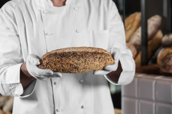 Man holding freshly baked bread in bakery