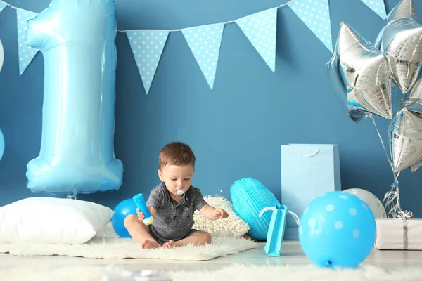 可爱的小男孩坐在地毯上装饰的第一个生日聚会的房间 — 图库照片