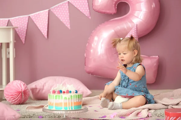 可爱的小女孩与美味的蛋糕坐在地毯上装饰的生日聚会 — 图库照片