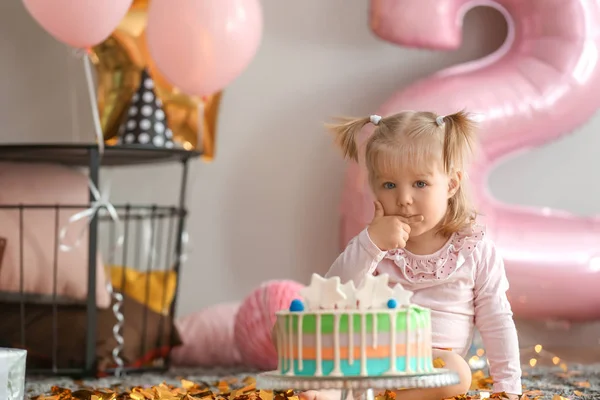 誕生日パーティーのための部屋のカーペットの上に座っておいしいケーキとかわいい女の子 — ストック写真