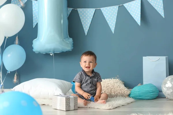 誕生日パーティーのための部屋でふわふわの敷物の上に座っているかわいい男の子 — ストック写真