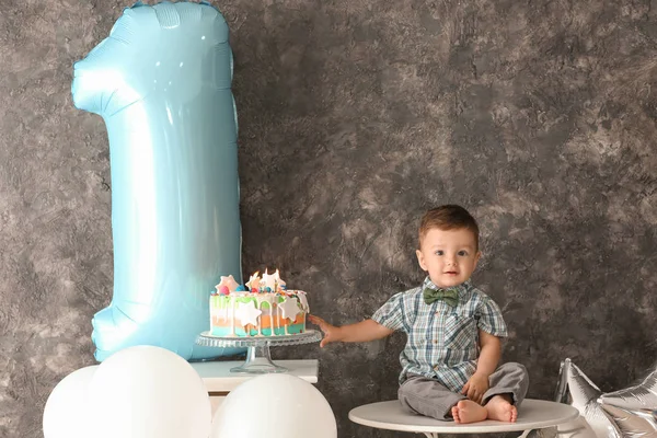 最初の誕生日パーティーのための部屋のテーブルの上に座っておいしいケーキとかわいい男の子 — ストック写真