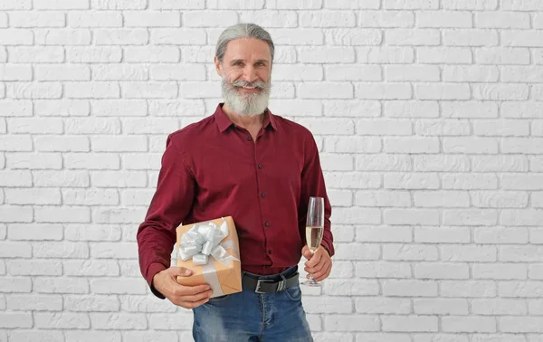 Зрелый Мужчина Подарком День Рождения Бокалом Шампанского Фоне Кирпичной Стены — стоковое фото
