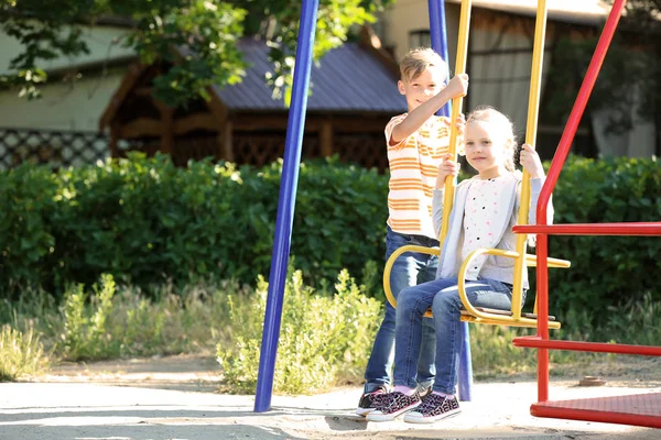 Cute Boy Pushing Little Girl Swings Outdoors — Stock Photo, Image