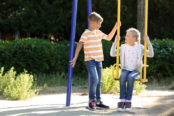 Cute Boy Pushing Little Girl Swings Outdoors — Stock Photo, Image