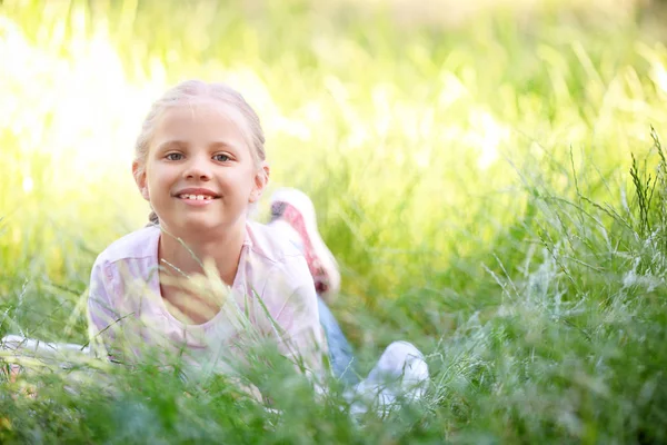 可爱的小女孩躺在绿色的草地上户外 — 图库照片