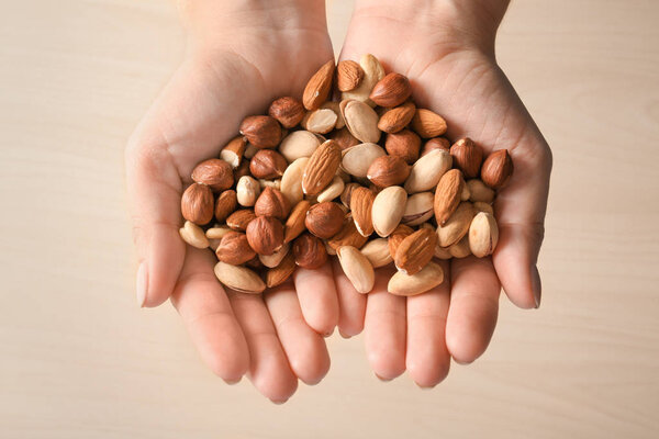 Woman holding different nuts on light background, closeup