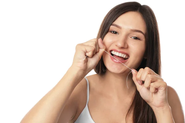 若い女性の白い背景の上の彼女の歯をフロス — ストック写真