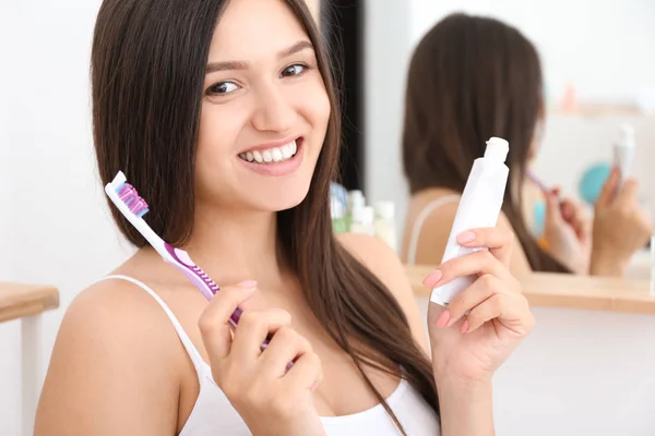 Young woman with toothpaste and brush in bathroom